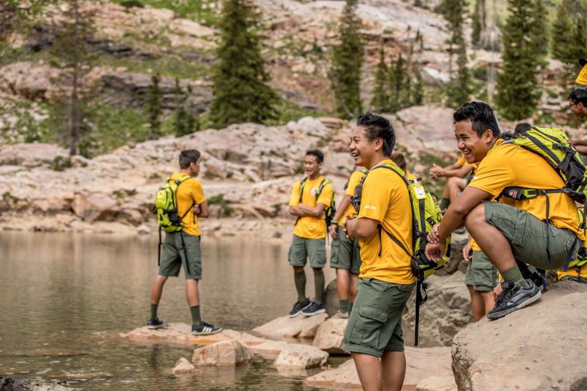Scouts by a mountain lake hiking and enjoying outdoor adventure activities surrounded by nature and rocky terrain.