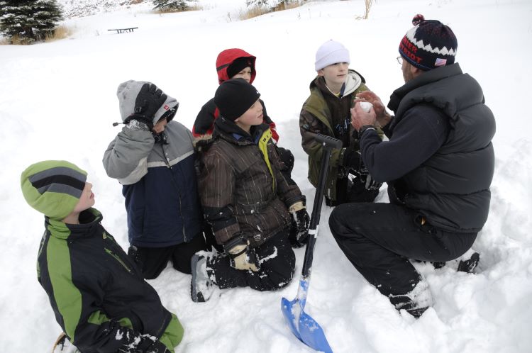Scoutmaster talks to Scouts on a winter camping trip in the snow